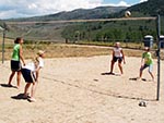 Two pairs of girls playing sand volleyball.