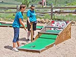 Young women aim for the clown's nose to win a prize at the ball return spot.