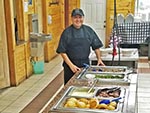 Chef Tony stands at the buffet table presenting his craft.