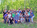 A youth group stands in front of trees for a photo.