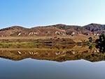 Looking across the lake, the mountains in the distance are nearly perfectly mirrored in the lake.