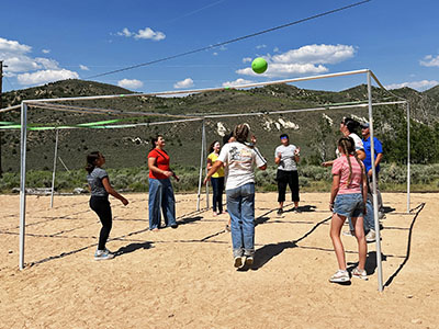 A group of people playing 9 Square in the Air on a sunny day.