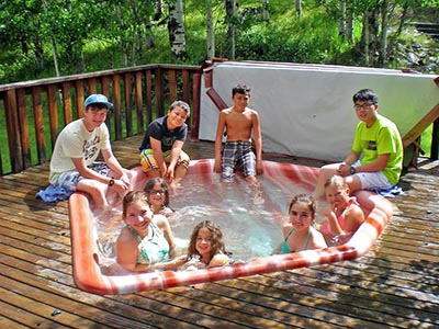 Children and teens relax in and around the hot tub on the Red Creek Lodge’s back deck.