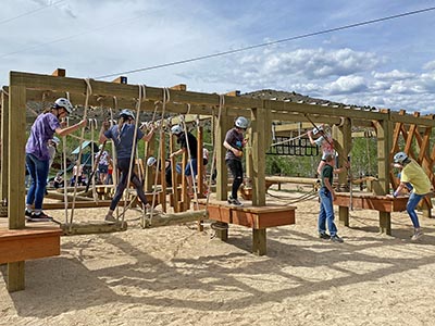 Lower Ropes Course showing some features: (foreground) log traverse, Tarzan swing, lattice boards, (background) upper and lower rope, log hops, virticle netting, and balance logs.