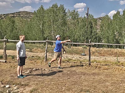 A player has tossed or 'pitched' a horseshoe toward the far metal stake.