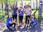 Young women and their leader pose with bows and arrows in hand.