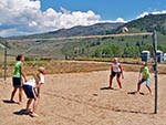 Two pairs of girls playing sand volleyball.