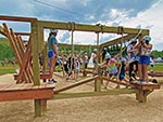 Lower Ropes Course showing some features: (foreground) lattice boards, hanging ropes with a log hill, (background) upper and lower rope, vertical netting, balance rope with hand holds.